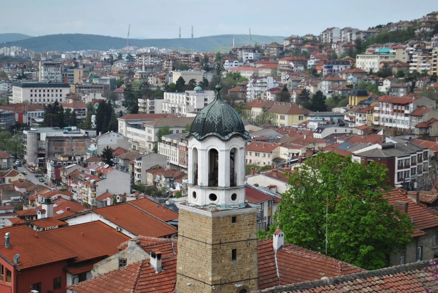 Red-roofed old town of Veliko Tarnovo seen from above, with a clock tower in the foreground